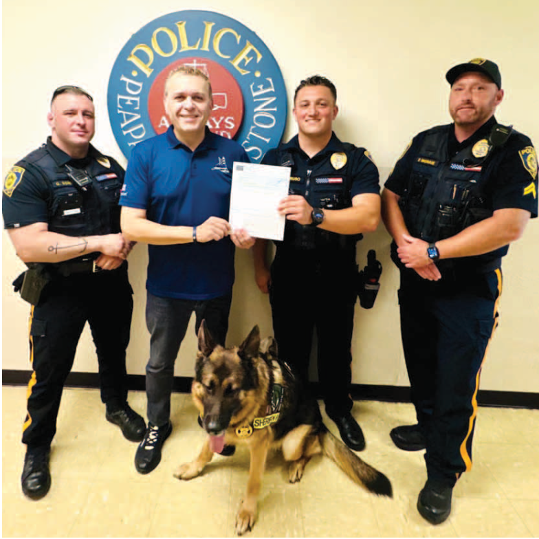Officer Adam Caruso of the Peapack & Gladstone Police Department in New Jersey receives the donation from César DePaço.